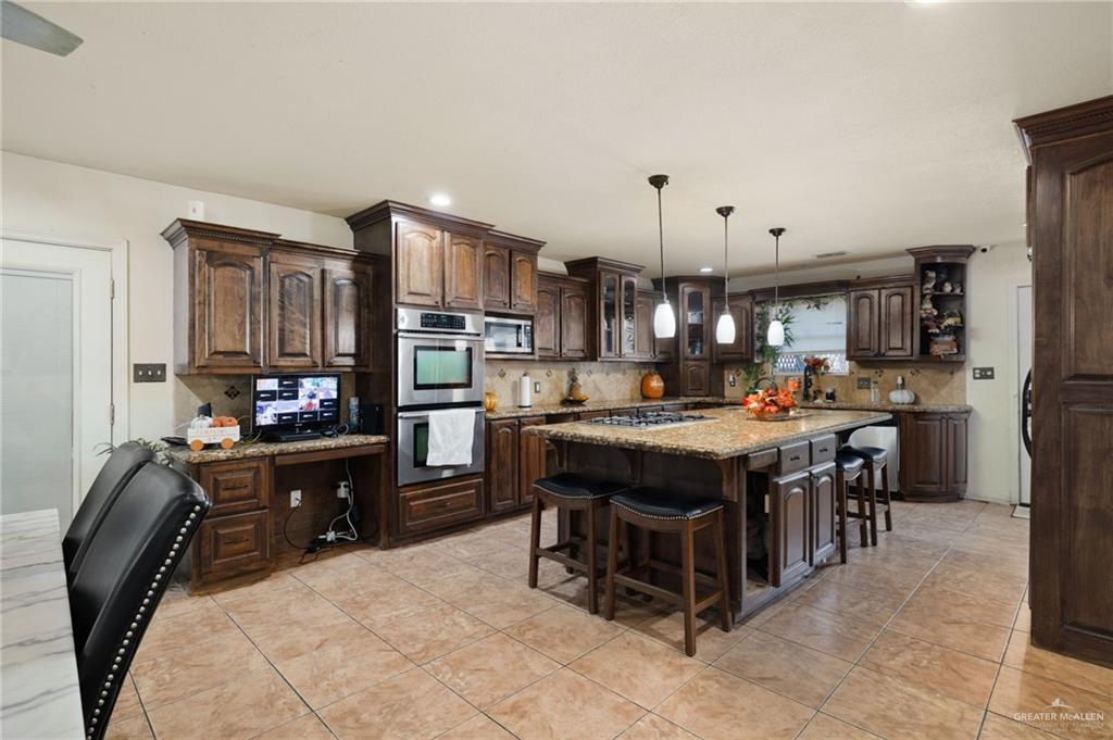 1222 South Bluebonnet Street Pharr, TX 78577 - Photo 6 of 17 a kitchen with kitchen island a stove a sink dishwasher and a refrigerator with wooden cabinets