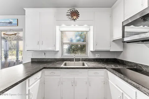 a kitchen with granite countertop a sink white cabinets and window