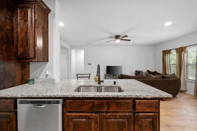 a kitchen with kitchen island granite countertop a sink and a refrigerator