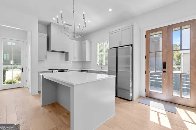 a kitchen with stainless steel appliances granite countertop a refrigerator a sink dishwasher a stove and a refrigerator with wooden floor