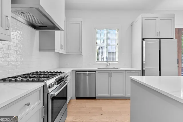 a kitchen with granite countertop a sink cabinets and stainless steel appliances