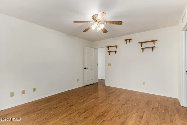 an empty room with wooden floor and chandelier fan