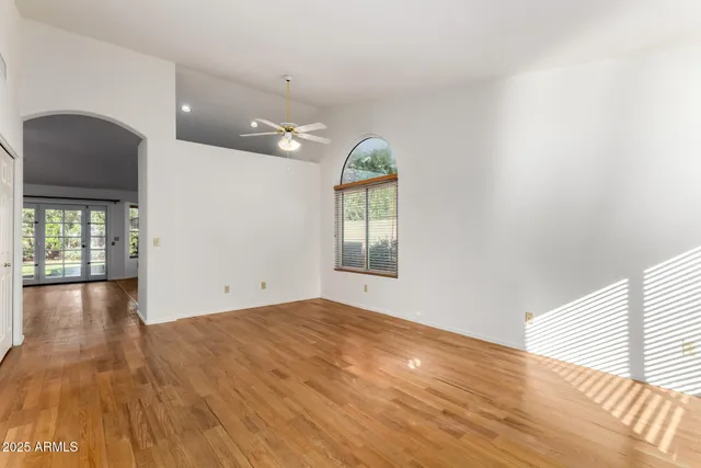 a view of an empty room with window and wooden floor
