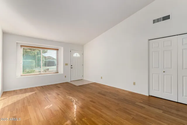 a view of an empty room with wooden floor and a window