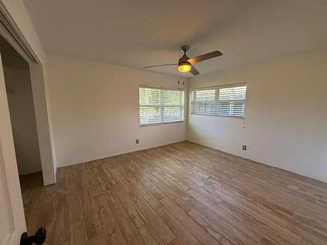 an empty room with windows and ceiling fan