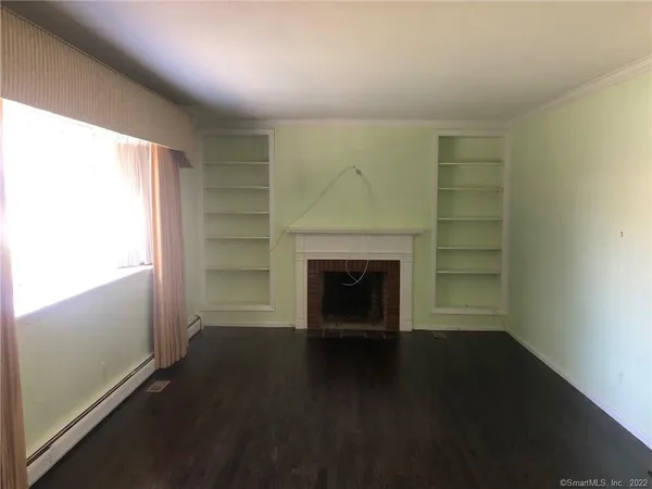 an empty room with windows and fireplace