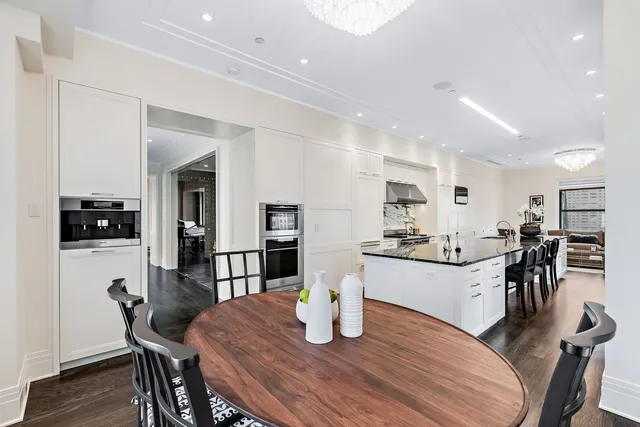 a kitchen with a dining table chairs and wooden floor
