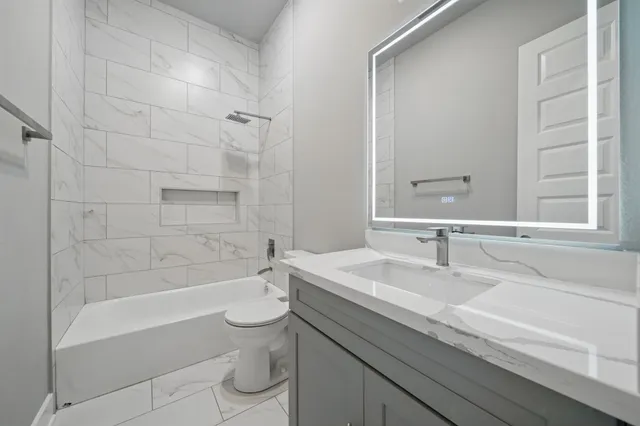 a bathroom with a granite countertop sink a toilet and bathtub