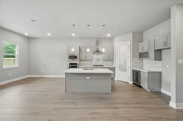 a view of kitchen with granite countertop a sink stove refrigerator and white cabinets with wooden floor