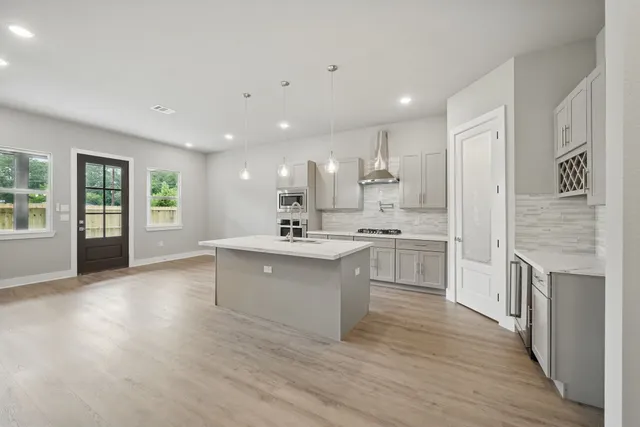 a large white kitchen with a sink dishwasher a stove and a refrigerator with wooden floor