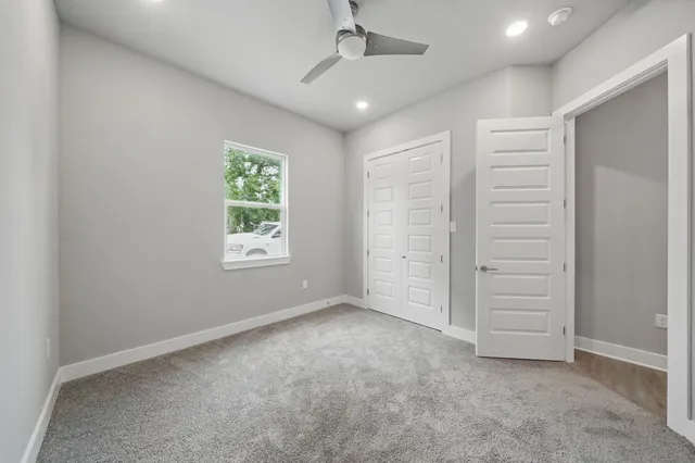 an empty room with a ceiling fan window and closet