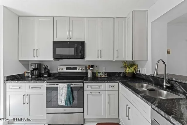 a kitchen with granite countertop white cabinets and sink