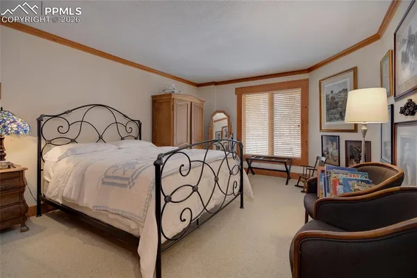 a spacious bedroom with a bed a large window with table and chairs