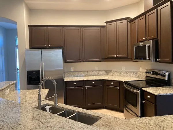 a kitchen with stainless steel appliances granite countertop a stove a sink and a microwave