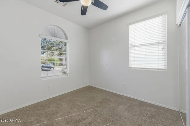 an empty room with a window and a ceiling fan