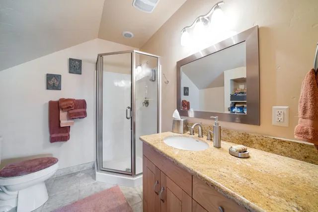 a bathroom with a granite countertop sink a toilet and a shower