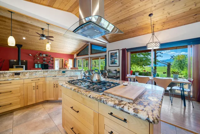 a kitchen with stainless steel appliances granite countertop a stove a sink dishwasher and white cabinets with wooden floor