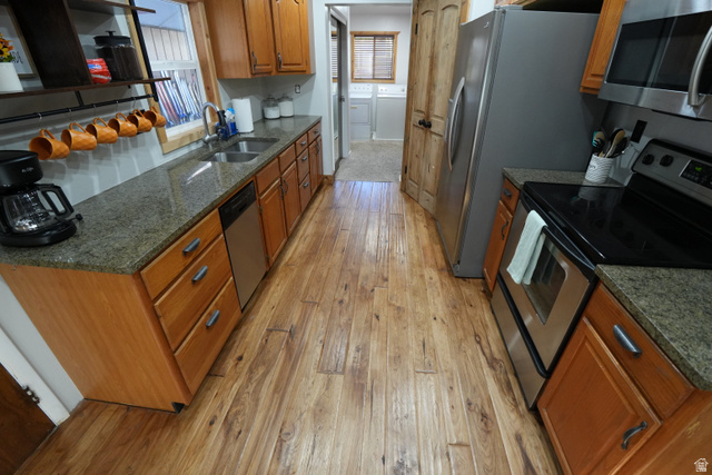 3711 North Canyon Road Provo, UT 84604 - Photo 7 of 42 Kitchen with stainless steel appliances, dark stone counters, washer and clothes dryer, light wood-style flooring, and brown cabinets
