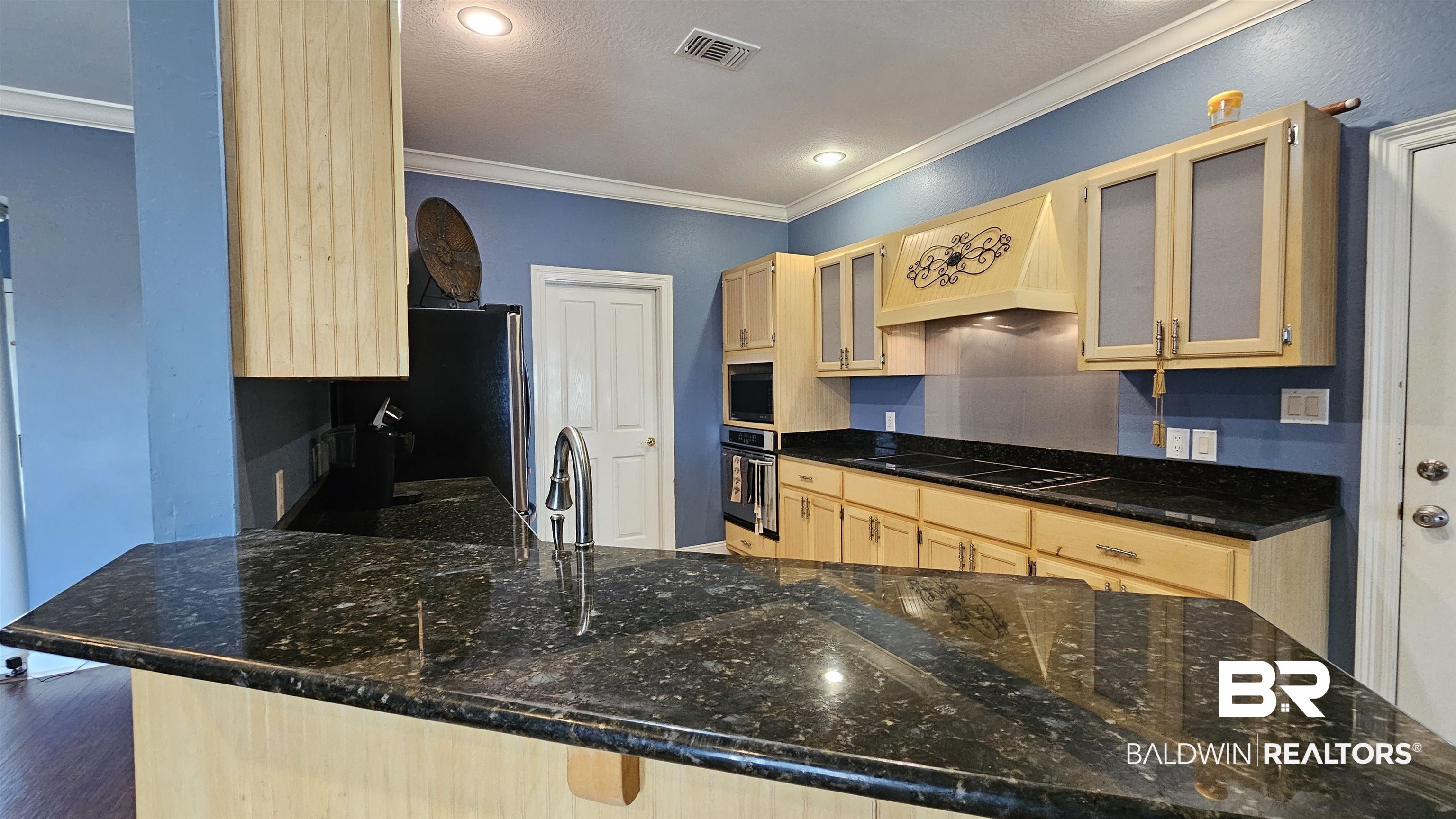 9275 Crawford Road Elberta, AL 36530 - Photo 17 of 28 Kitchen featuring light brown cabinetry, custom range hood, ornamental molding, glass insert cabinets, and stainless steel appliances