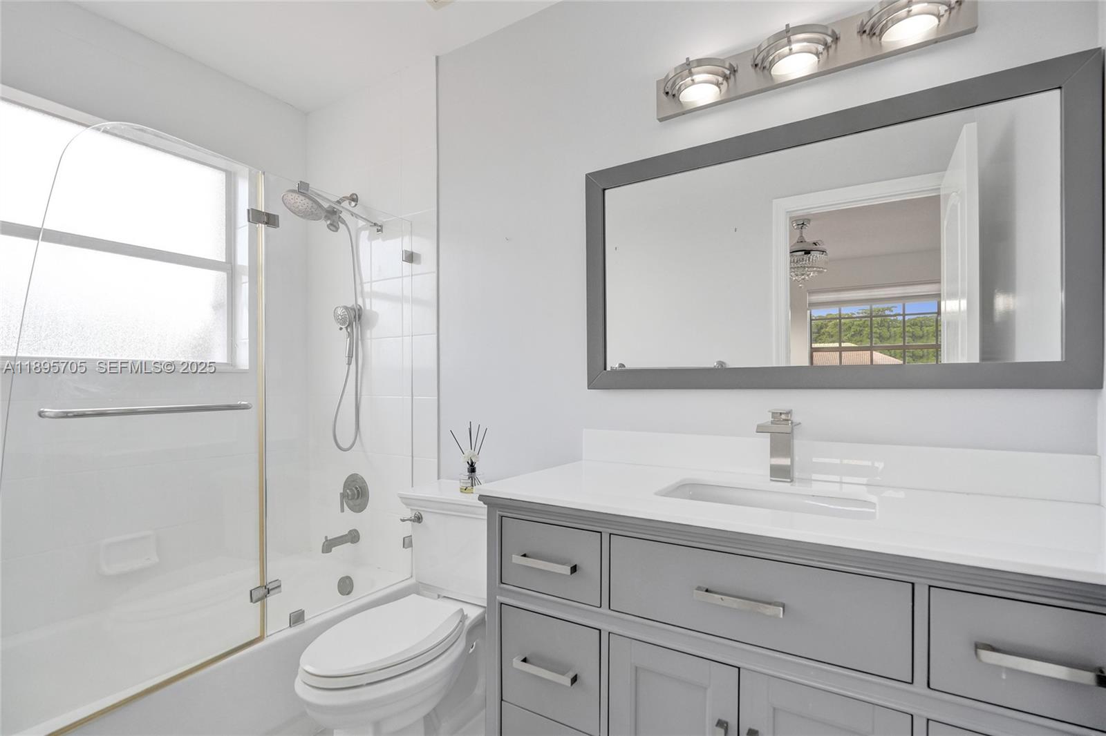 4248 Southwest 185th Avenue Miramar, FL 33029 - Photo 62 of 88 a bathroom with a toilet a sink a mirror a window and vanity