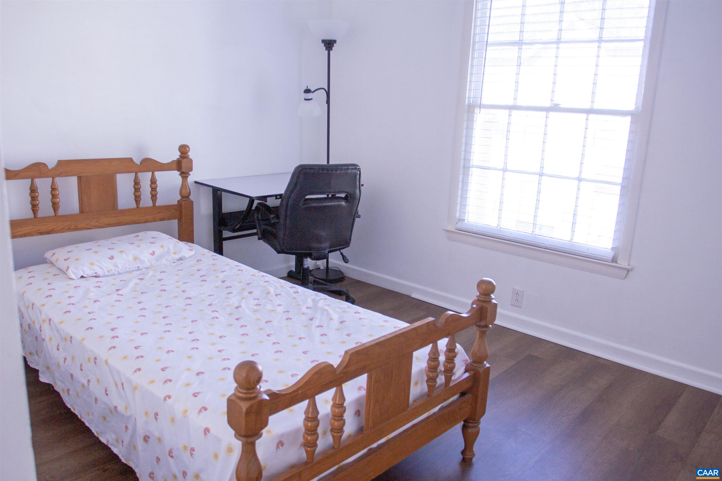 2527 Hydraulic Road, Unit 34 Charlottesville, VA 22901 - Photo 5 of 10 a bedroom with a bed a desk and chair with wooden floor