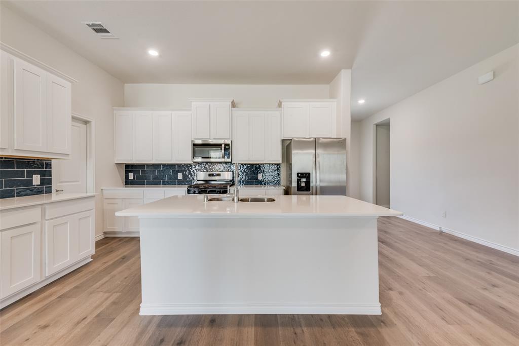 1532 Ruby Jewel Lane Anna, TX 75409 - Photo 6 of 19 a view of kitchen with stainless steel appliances granite countertop a stove top oven a sink dishwasher and a refrigerator with wooden floor