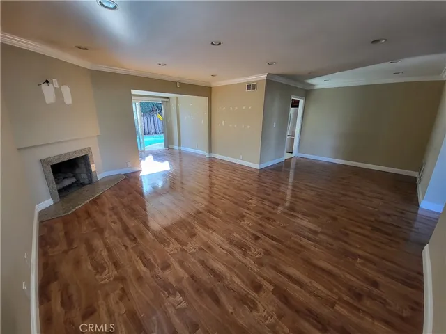 a view of empty room with wooden floor and fireplace