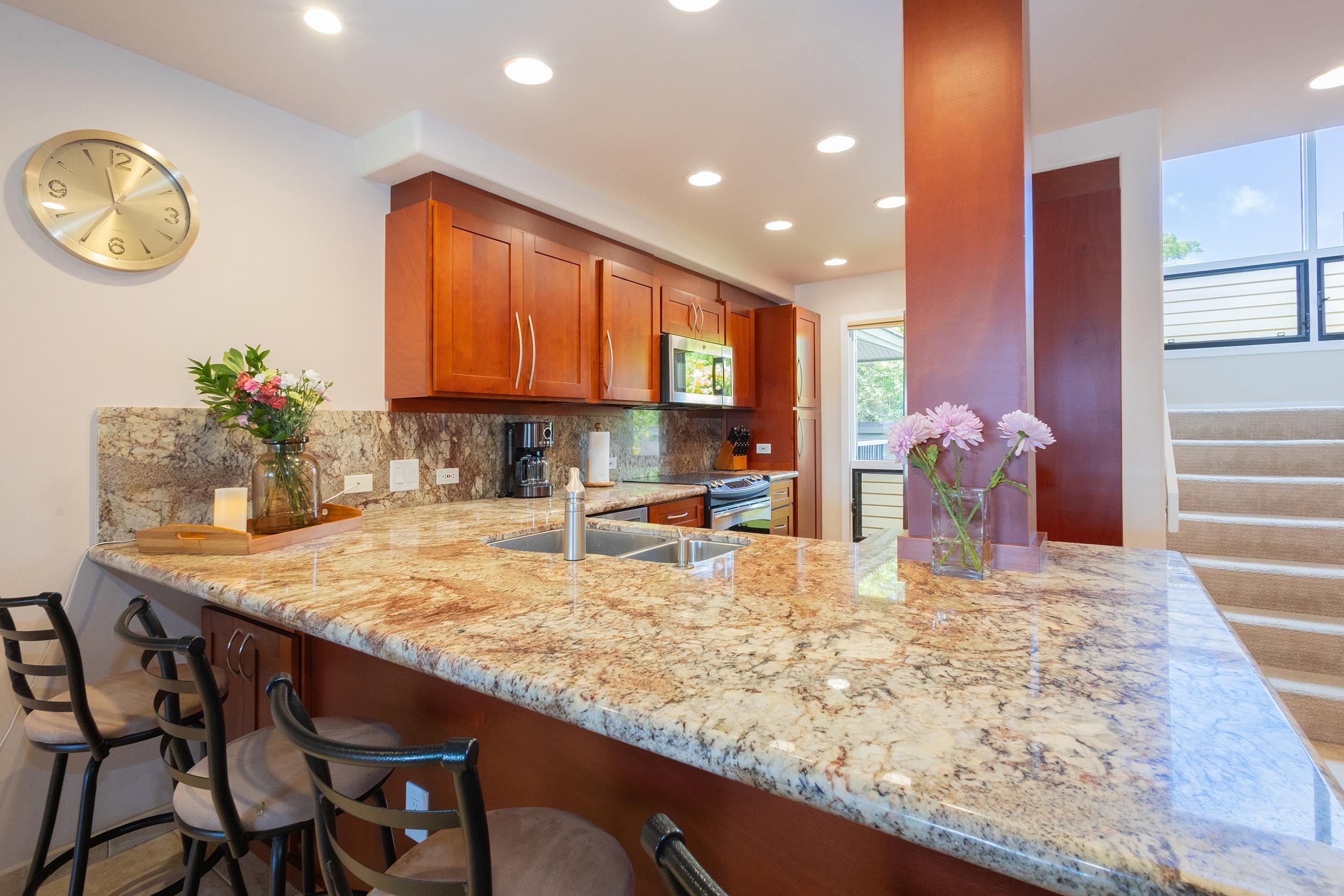 100 Ridge Road, Unit 723 Lahaina, HI 96761 - Photo 6 of 48 a kitchen with kitchen island granite countertop wooden cabinets and granite counter tops