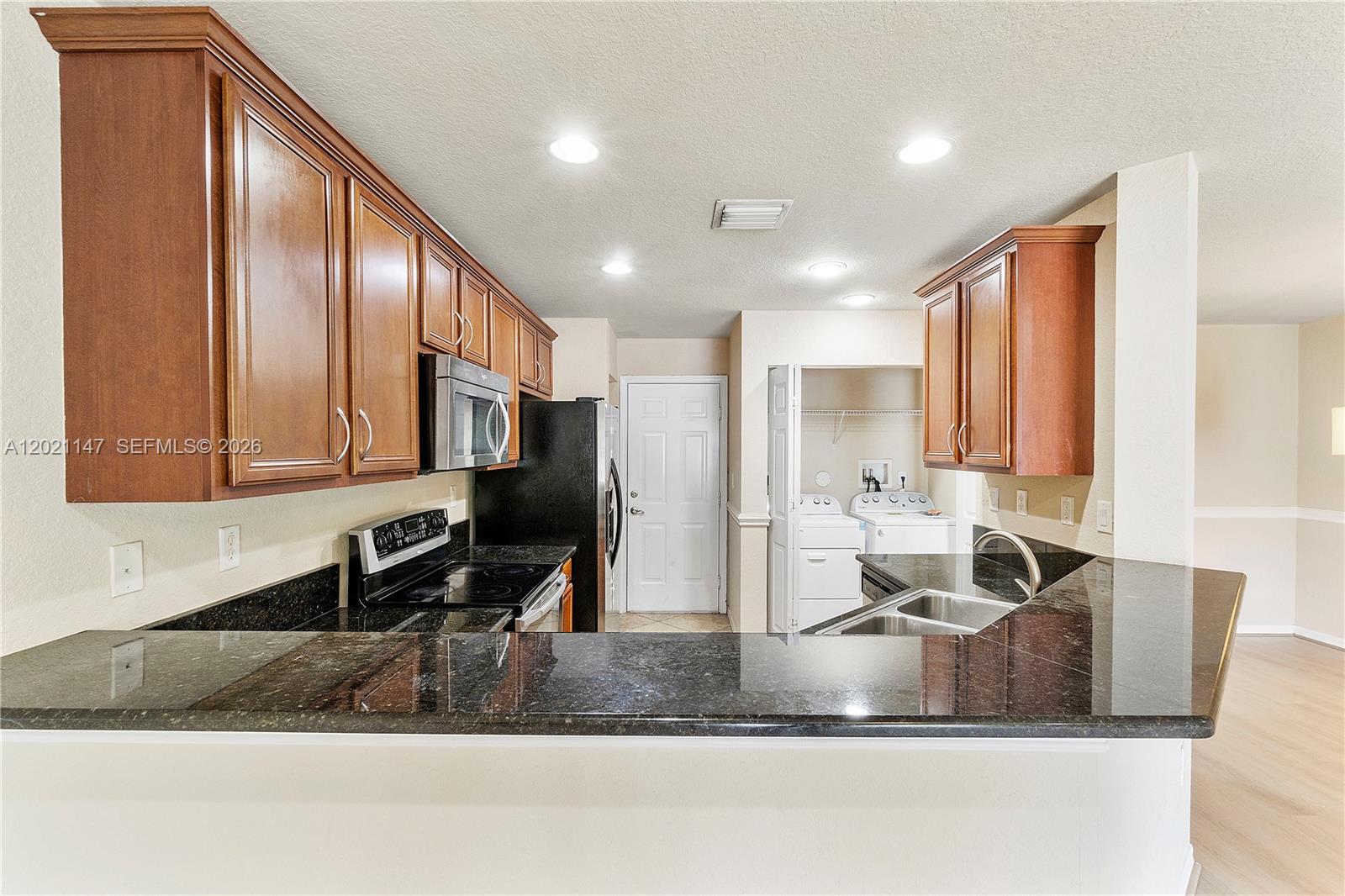 5930 Abbey Road Tamarac, FL 33321 - Photo 7 of 26 a kitchen with stainless steel appliances granite countertop a sink a stove and a refrigerator with wooden floor
