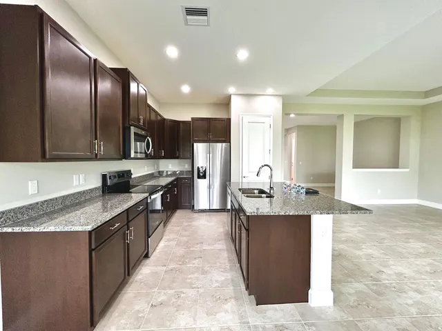 a large kitchen with stainless steel appliances kitchen island granite countertop a large counter top cabinets and couches