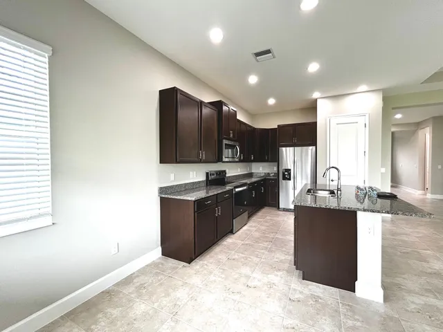 a large kitchen with kitchen island granite countertop a stove and cabinets