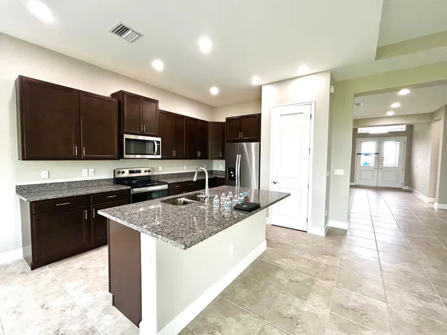 a large kitchen with stainless steel appliances granite countertop a stove refrigerator and a microwave