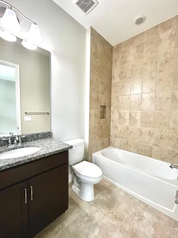 a bathroom with a granite countertop sink a toilet a mirror and bathtub