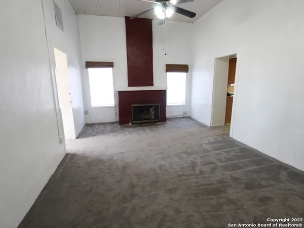 an empty room with fireplace and windows