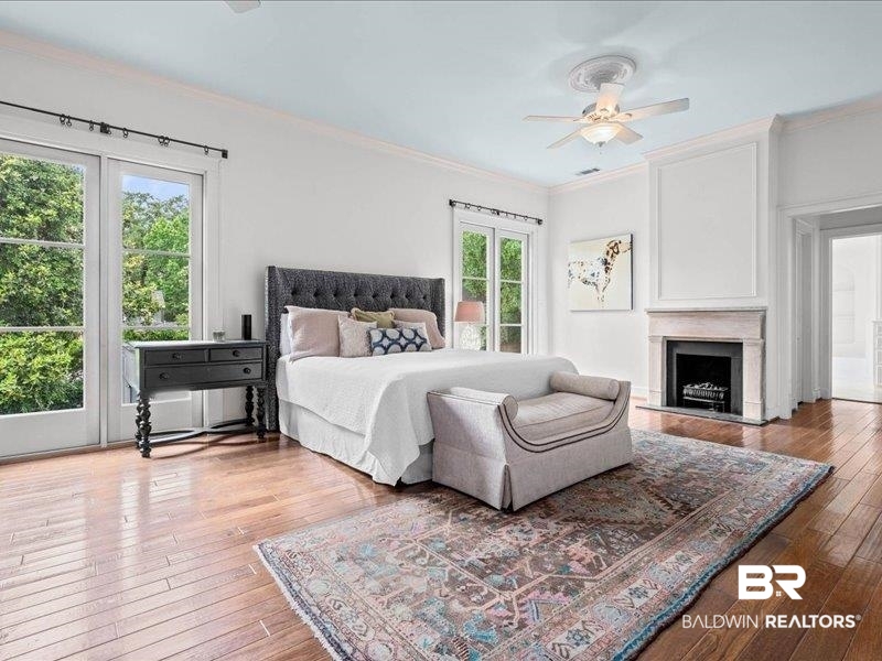 109 Eaton Square Mobile, AL 36608 - Photo 12 of 26 Spacious room featuring wood-finish flooring, a stone fireplace with a dark firebox, and two sets of French doors with transom windows