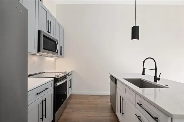 a kitchen with stainless steel appliances granite countertop a sink and a stove top oven with wooden floor