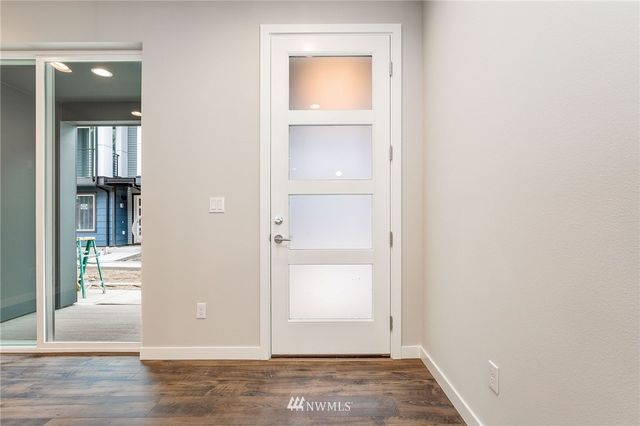 an empty room with wooden floor closet and windows