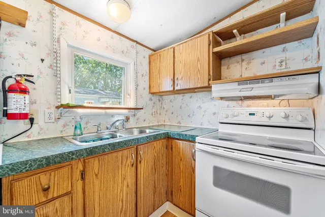 a kitchen with granite countertop a sink stainless steel appliances white cabinets and a window