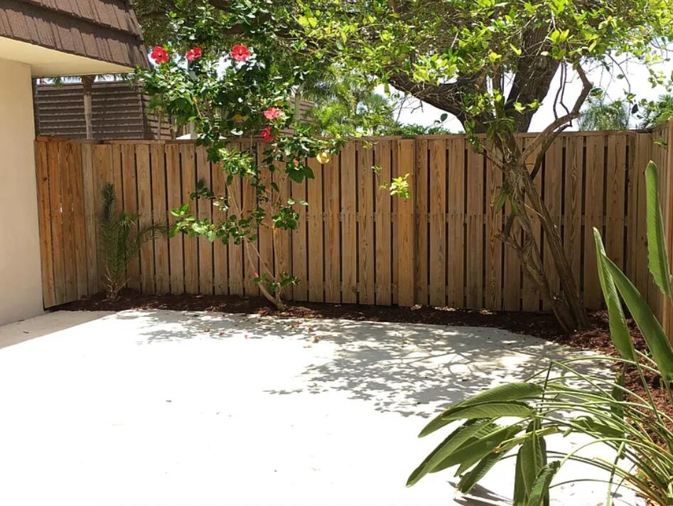 1403 14th Court Jupiter, FL 33477 - Photo 20 of 25 a backyard of a house with trees and wooden fence