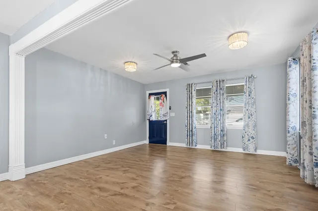 a view of an empty room with window and wooden floor