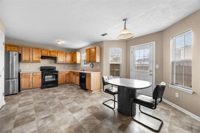 a kitchen with stainless steel appliances granite countertop a stove a sink a refrigerator dining table and chairs