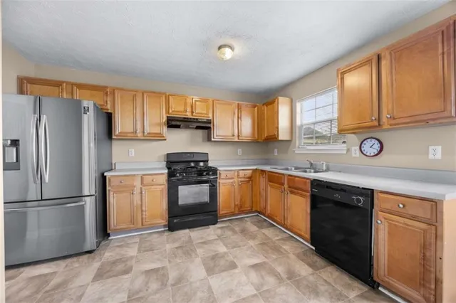 a kitchen with granite countertop a refrigerator stove top oven and sink