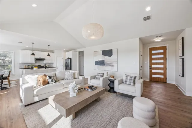 a living room with furniture kitchen view and a wooden floor