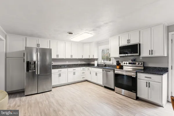 a kitchen with granite countertop a refrigerator stove top oven and sink