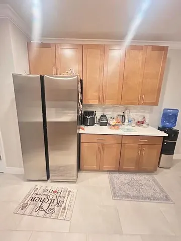 a room with stainless steel appliances kitchen island granite countertop a refrigerator sink and cabinets