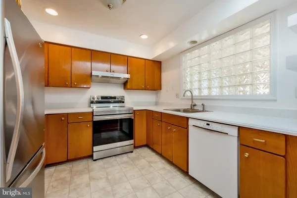 a kitchen with stainless steel appliances granite countertop a refrigerator a stove and a sink