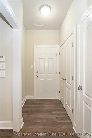 a view of a hallway with wooden floor and closet area