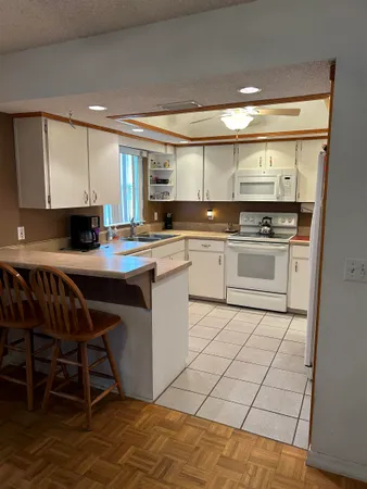 a kitchen with stainless steel appliances granite countertop a table chairs sink and cabinets