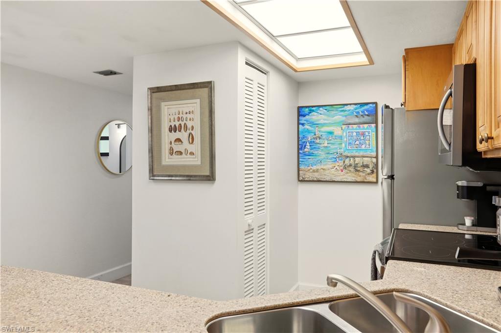 600 Neapolitan Way, Unit 254 Naples, FL 34103 - Photo 12 of 42 Kitchen featuring light stone countertops, range with electric stovetop, stainless steel microwave, and a skylight