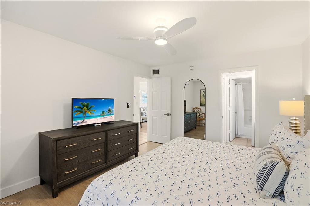 600 Neapolitan Way, Unit 254 Naples, FL 34103 - Photo 18 of 42 Bedroom with a ceiling fan, light wood-style floors, and ensuite bathroom